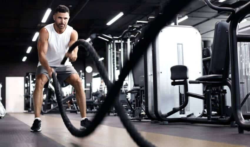 How to Increase Stamina: A man doing battle rope in the gym