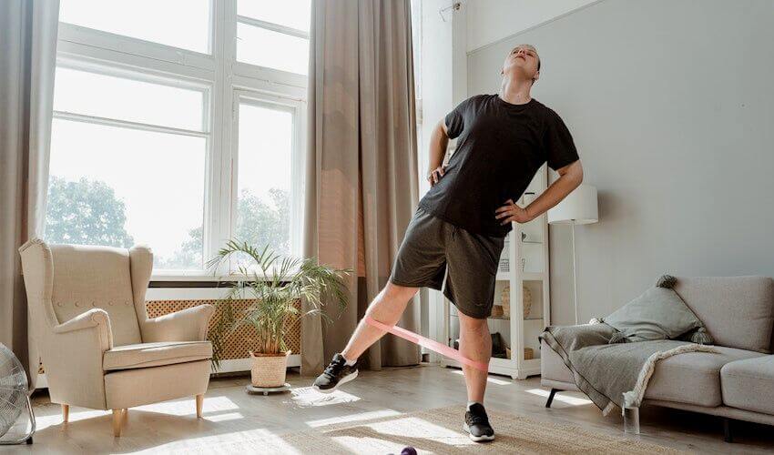 11 Best Gluteus Medius Exercises - A man doing banded hip abduction at home